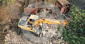 Demolition of old house, aerial view. Excavator breaks building for new housing