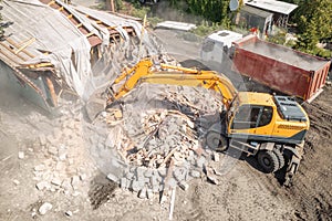 Demolition of old house building for new construction by excavator bucket, aerial view. City development