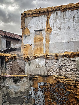 A demolition of an old house in a historic district, with walls with yellow or ochre polyurethane foam and deteriorated brick