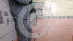 Demolition of old tiles with jackhammer. Renovation of old walls in the bathroom or kitchen