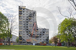Demolition of a tall apartment building. Crane with boom and nibbler photo