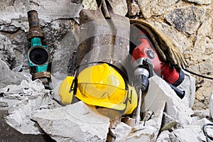 Demolition of walls. Electric hammer helmet and hearing protection lying on the rubble. Old brick and remodeled building wall.