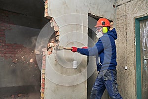 Demolition work and rearrangement. worker with sledgehammer destroying wall