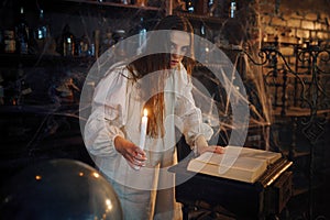 Demonic woman with candle reads book of spells