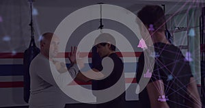 Demonstrating instructor guiding student through wrist control move in gym, with network overlay