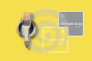 Demonstrating trendy Color of the Year 2021. Illuminating Yellow and Ultimate Gray. Brush and open paint can with on