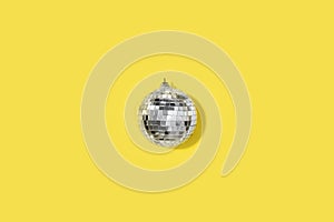 Demonstrating trendy Color of the Year 2021. Illuminating Yellow and Ultimate Gray. Grey mirror disco ball on yellow