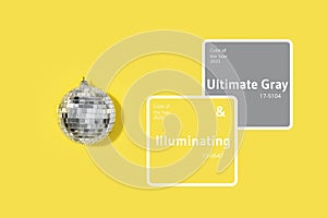 Demonstrating trendy Color of the Year 2021. Illuminating Yellow and Ultimate Gray. Grey mirror disco ball on yellow