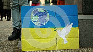 Demonstration people against Russian military attack war Russia on Ukraine flag, banner of hope doves planet earth crowd