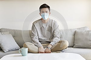 Demoralized young asian man staying at home wearing mask looking at camera