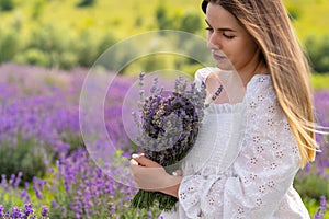 Demure beautiful young woman posing with bunch of lavender