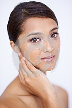 Demure Beauty. A gorgeous young woman feeling her smooth, soft skin in a studio shoot.