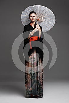 Demure beauty. Studio fashion shot of a young woman wearing oriental-style clothing.