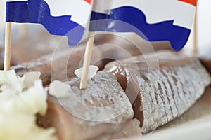 Den Helder, Netherlands. June 2022. Close up of raw herring with dutch flag and onions.