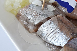 Den Helder, Netherlands. June 2022. Close up of raw herring with dutch flag and onions.