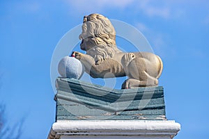 Den Helder, Noord-Holland, Netherlands, April 17, 2021. Side view of a statue of a golden lion with its front legs on a ball