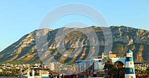 Denia Spain. View of Mount Montgo and the city from afar, beautiful colorful buildings, sunset, blue sky