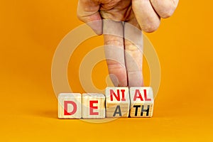 Denial death symbol. Concept words Denial Death on wooden block. Beautiful orange table orange background. Businessman hand.