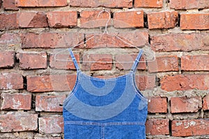 Denim blue women dress hanging on a hanger on a brick wall in the street, women clothing