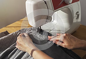 Denim cloth on sewing machine closeup. Seamstress work process concept
