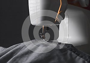 Denim cloth on sewing machine closeup. Small business concept