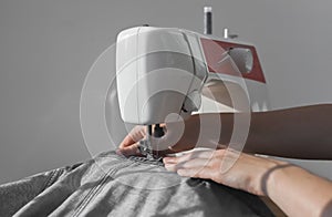 Denim cloth on sewing machine closeup. Women hands at manual work
