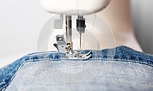 Denim clothing on sewing machine close up