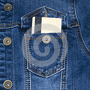 Denim jacket pocket with stitches. Casual wear. Jean jacket. A plastic credit card sticks out of his pocket.