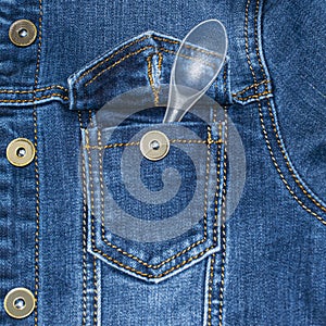 Denim jacket pocket with stitches. Casual wear. Jean jacket. A plastic disposable spoon sticks out of a pocket