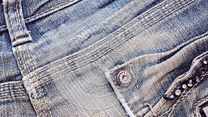 Denim jeans fabric texture with seam, studs and pocket.
