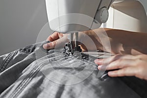 Denim or jeansecloth on sewing machine closeup. Seamstress hands at work process