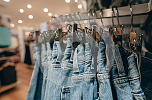 Denim pants in clothing store. Jeans on hanger hanging on rack in clothing store. Fashion retail shop inside shopping mall.