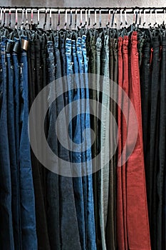 Denim pants in different colors on hangers in a clothing store. The concept of shopping and sales. Background for design on the th