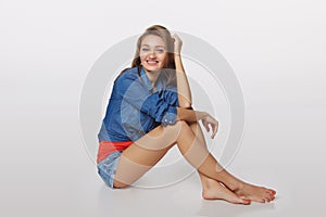 Denim style portrait of teen girl on the floor, over gray background