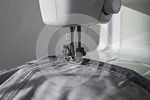 Denim textile on sewing machine closeup. Small business and slow fashion concept