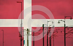 Denmark flag with tram connecting on electric line with blue sky as background, electric railway train and power supply lines