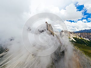 Dense fog covered rocky peak of Seceda mountain in Alps