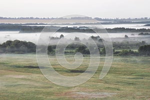 Dense fog over summer morning fields meadows and forests