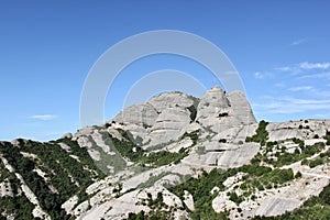 Dense green vegetation is located in the hollows of high stone cliffs.