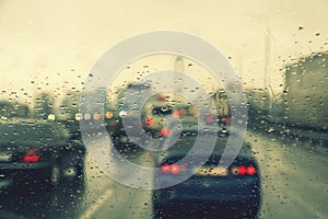 Dense traffic on a rainy day. Traffic in rainy day with road view through car window with rain drops. Blurry image, Rain