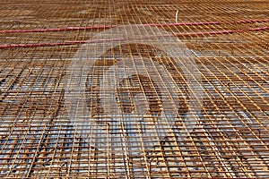 Densely laid rusted metal construction net on top of strong concrete foundation at local building construction site