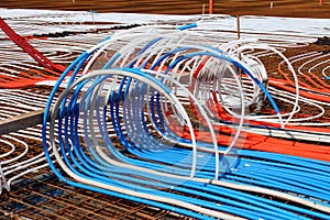 Densely put plastic water pipes endings laid on top of rusted metal construction net for installation of radiant floor heating