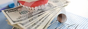Dental artificial jaw instrument and one hundred dollar bills on dentist desk