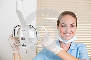 Dental assistant smiling at camera beside light photo