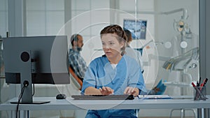 Dental assistant using computer and x ray scans at desk