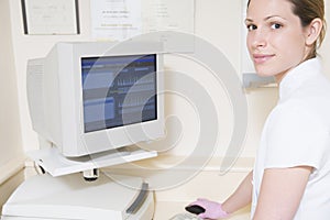 Dental assistant using computer smiling