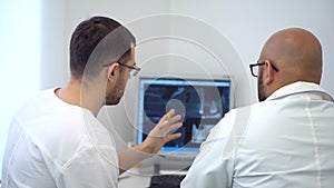 Dental assistent discussing with dentist about the tooth`s problem on x-ray shot