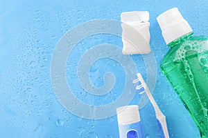 Dental care and oral hygiene concept with a bottle of green mouthwash, toothbrush, dental floss and tube of toothpaste soaked in