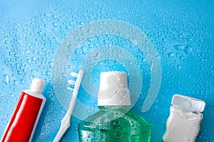 Dental care and oral hygiene concept with a bottle of green mouthwash, toothbrush, dental floss and tube of toothpaste soaked in