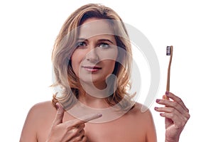 Dental care, oral hygiene and people concept - portrait of happy smiling woman holding wooden toothbrush over white background